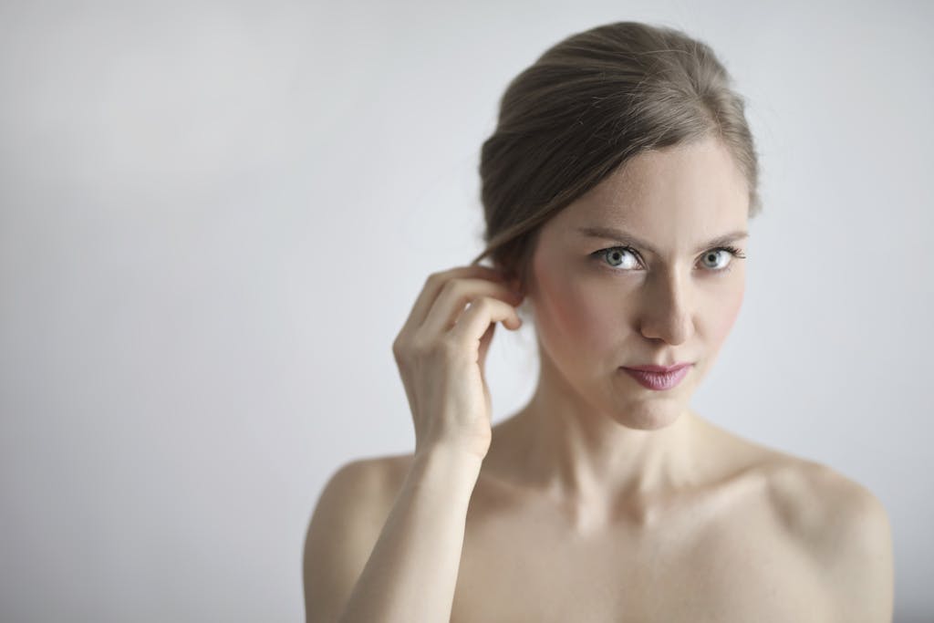 Close-up portrait of a young woman with natural makeup, showcasing elegance and beauty with a soft white background.